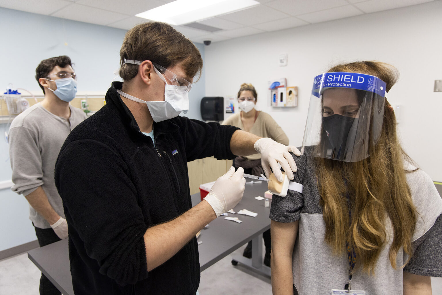 Second year medical student Oliver Davidson practices injecting a vaccine into a pad on the arm of physician and faculty member Dr. Carrie Kelly during hands on training in the clinical skills lab at the Medical Partnership on the Health Sciences Campus. Second year students will be helping at COVID vaccination centers in the local area in the coming weeks.